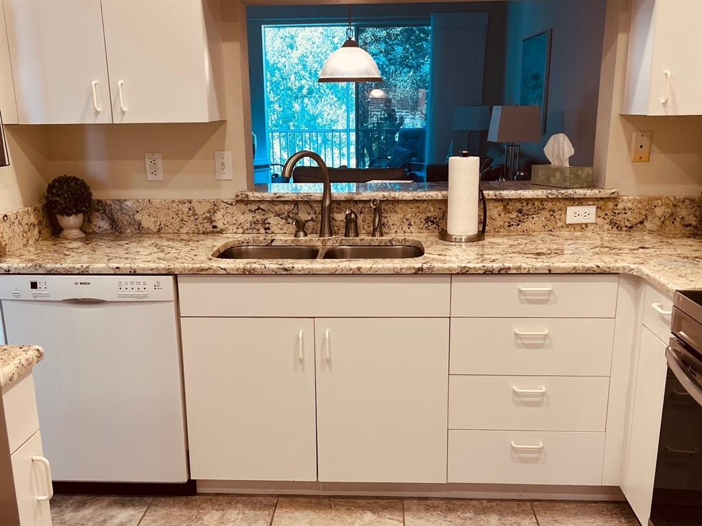 A kitchen features white cabinets, granite countertops, a double sink, and a stainless steel dishwasher — 9630 CLUB SOUTH CIRCLE UNIT 6201, SARASOTA, FL