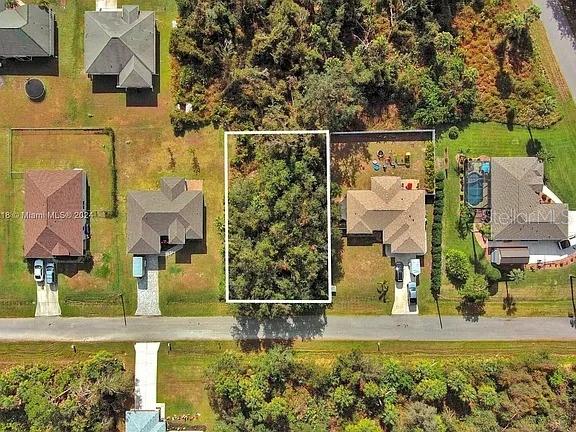 An aerial view shows a vacant, tree-covered residential lot situated between two developed properties — SARGON AVENUE, NORTH PORT, FL