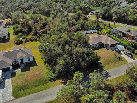 An aerial view shows a vacant, wooded lot situated between two suburban residential homes — SARGON AVENUE, NORTH PORT, FL