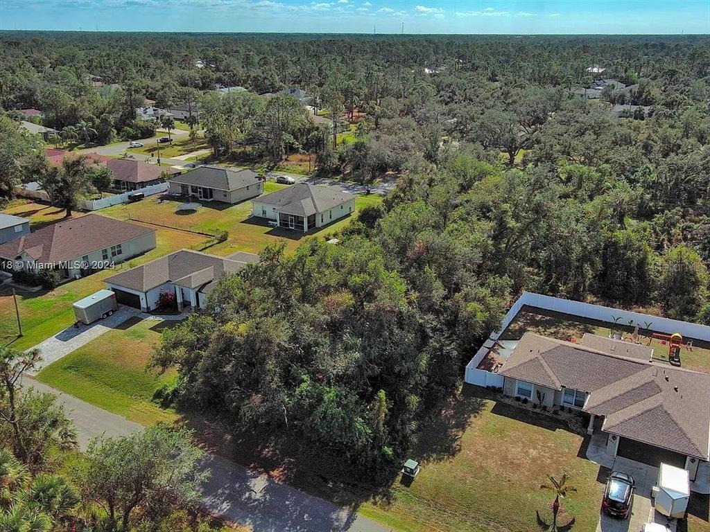 An aerial view shows several suburban houses surrounded by dense trees and a vacant lot — SARGON AVENUE, NORTH PORT, FL