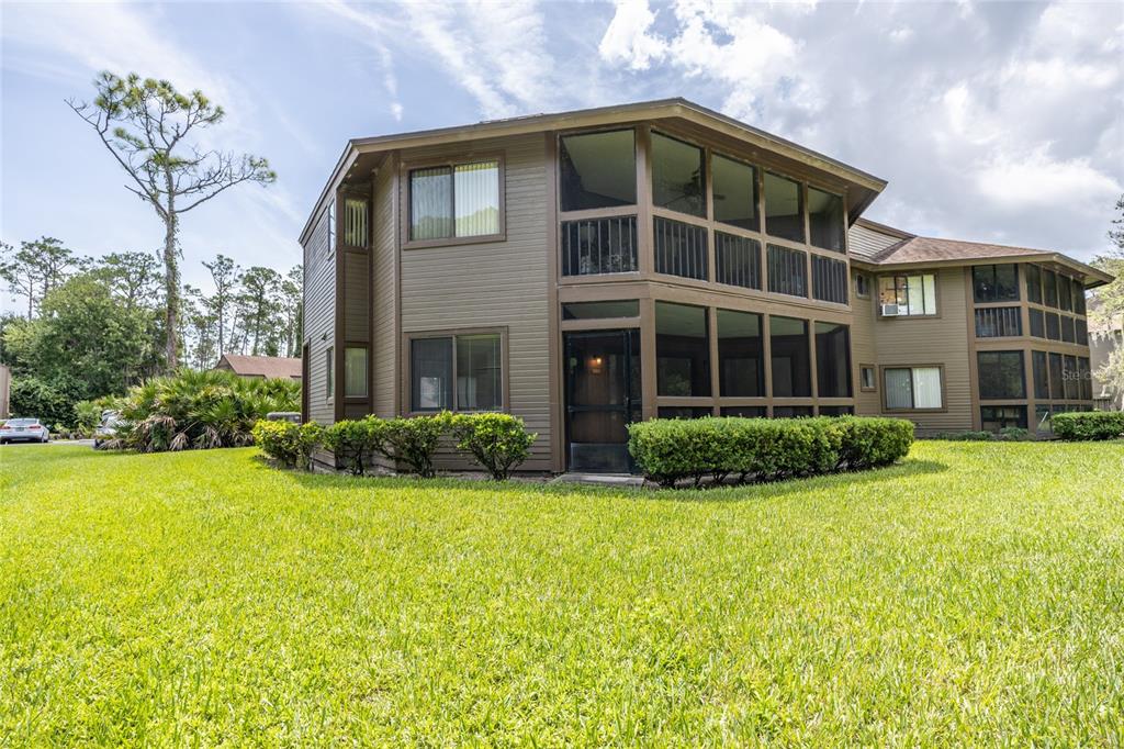 A two-story brown building with screened-in porches and surrounding green lawn — 9 SOUTHBURY COURT UNIT 9, PALM COAST, FL