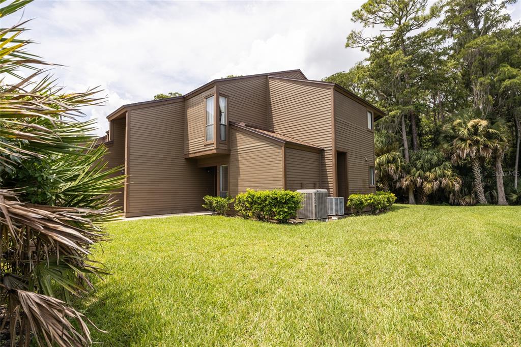 A brown two-story townhouse exterior sits on a grassy lawn near a wooded area — 9 SOUTHBURY COURT UNIT 9, PALM COAST, FL