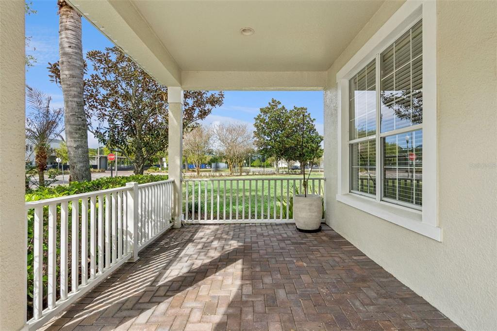 A covered porch features brick pavers, a white railing, and a view of a grassy area — 14255 SONCO AVENUE, WINDERMERE, FL