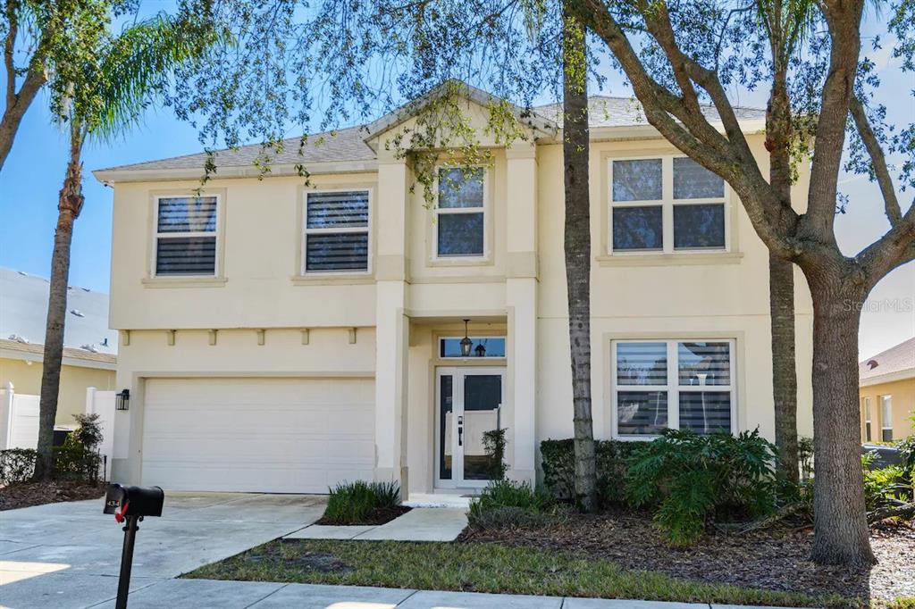 A two-story, light-colored suburban house with a two-car garage and a front entrance — 434 HENLEY CIR, DAVENPORT, FL
