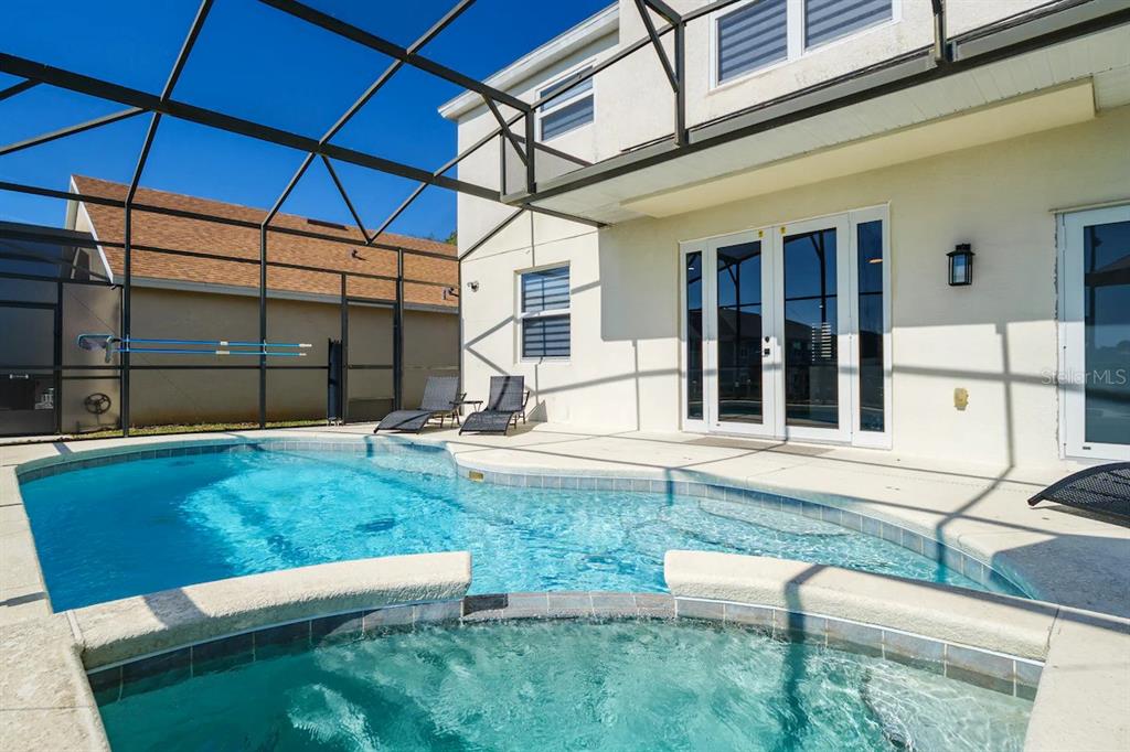 A screened-in patio features a swimming pool, a hot tub, and lounge chairs — 434 HENLEY CIR, DAVENPORT, FL