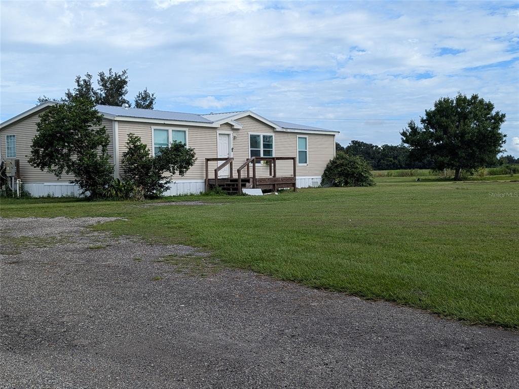 A single-story manufactured home with light siding sits on a large, grassy lot — 1291 NE HANSEL AVENUE, ARCADIA, FL