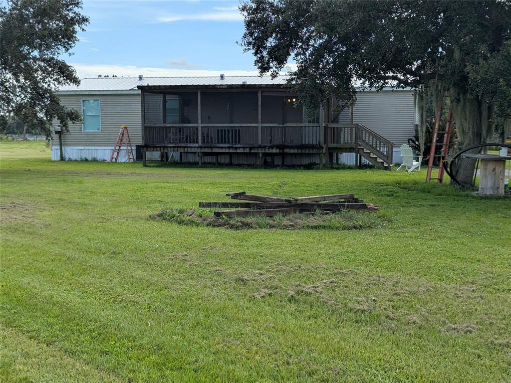 A single-story manufactured home features a large screened-in porch and a spacious grassy yard — 1291 NE HANSEL AVENUE, ARCADIA, FL