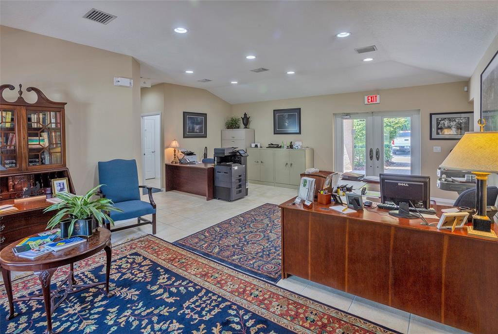 An office space features wooden desks, a printer, blue armchairs, and patterned area rugs — 310 WILDWOOD WAY, BELLEAIR, FL