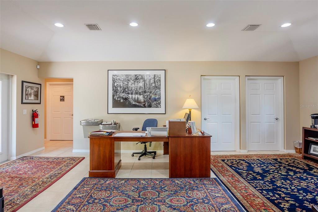 An office features a wooden desk, two area rugs, and three white doors — 310 WILDWOOD WAY, BELLEAIR, FL
