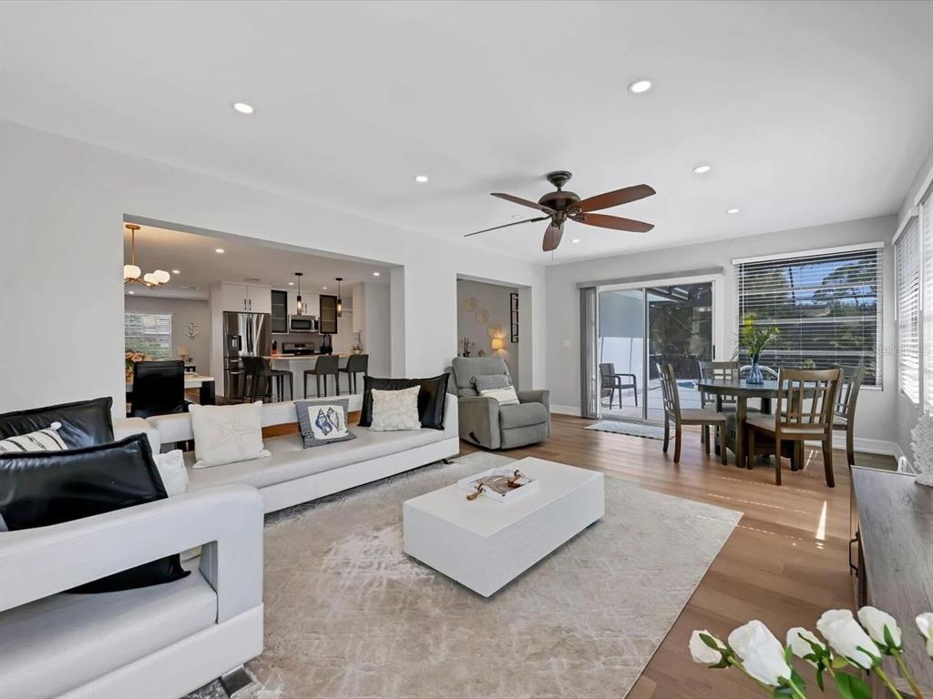 A bright living room with white furniture, a grey area rug, and an open kitchen — 2428 WHIPPOORWILL CIRCLE, SARASOTA, FL