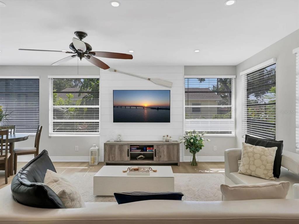 A living room features a white shiplap accent wall with a mounted television and paddle — 2428 WHIPPOORWILL CIRCLE, SARASOTA, FL