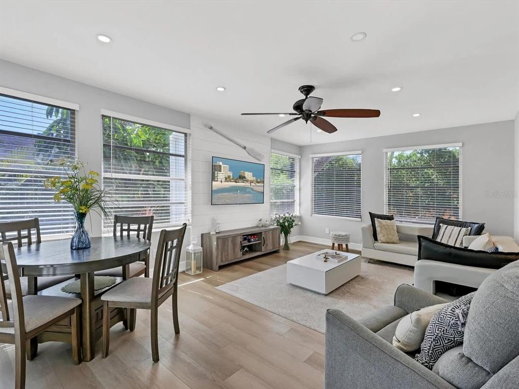 A bright living and dining area features light wood floors, white shiplap walls, and large windows — 2428 WHIPPOORWILL CIRCLE, SARASOTA, FL