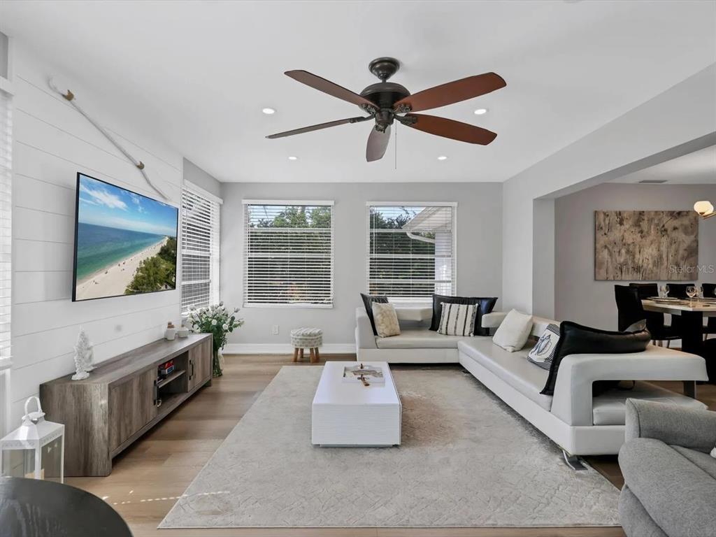 A living room features white shiplap walls, a sectional sofa, and a wooden media console — 2428 WHIPPOORWILL CIRCLE, SARASOTA, FL