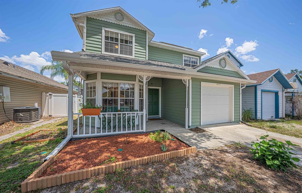 A two-story green house with a front porch, a garage, and a landscaped front yard — 6673 RYAN CHASE COURT, ORLANDO, FL