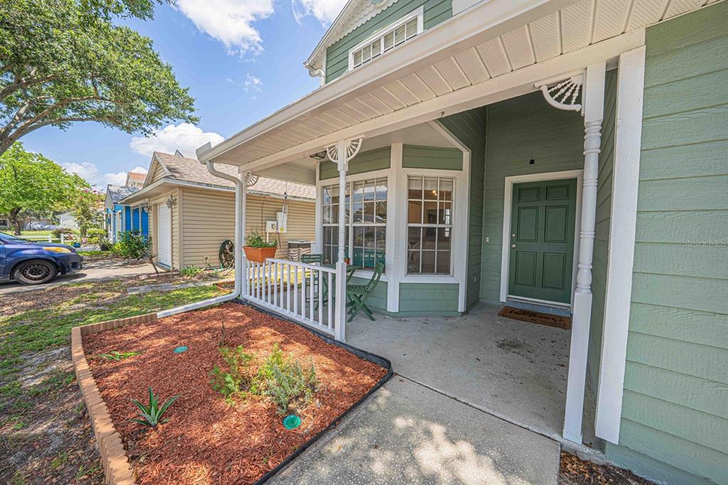A green house with a covered front porch, white railings, and a small garden bed — 6673 RYAN CHASE COURT, ORLANDO, FL