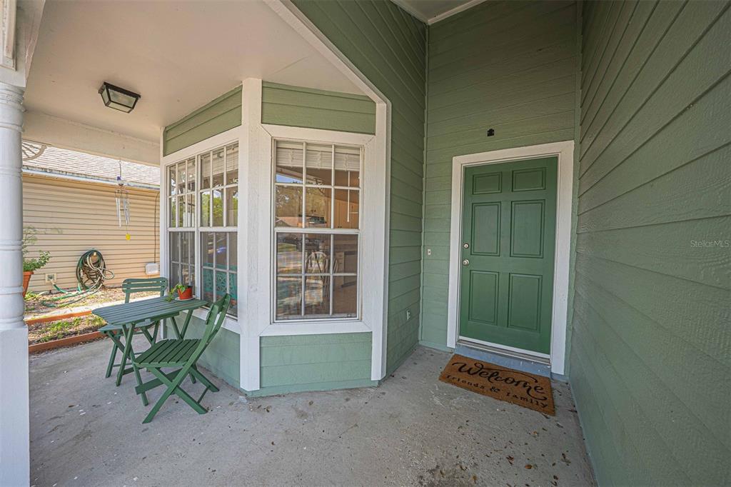 A covered front porch features green siding, a matching door, and a small bistro set — 6673 RYAN CHASE COURT, ORLANDO, FL