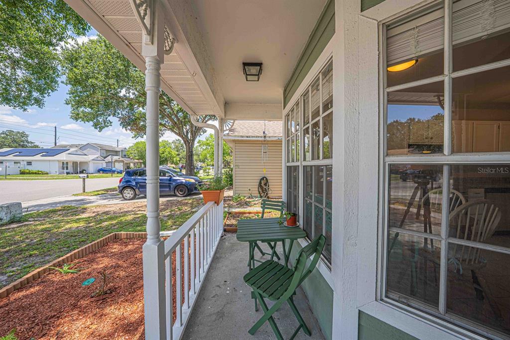 A covered front porch features a small green table and chairs beside a large window — 6673 RYAN CHASE COURT, ORLANDO, FL
