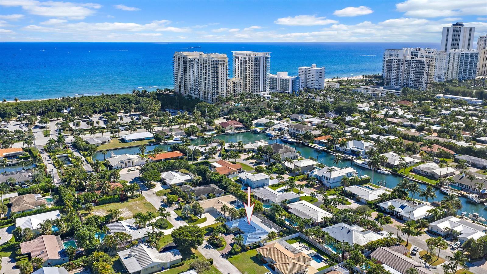 An aerial view shows a residential neighborhood with a canal and high-rise buildings nearby — 1211 Dolphin Road, Riviera Beach FL 33404, RIVIERA BEACH, FL