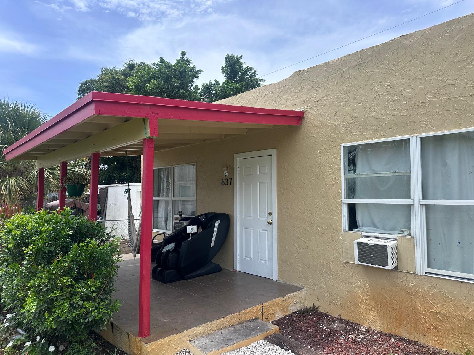 The exterior of a tan house features a red-trimmed porch, a white door, and windows — 637 46th Street, West Palm Beach FL 33407, WEST PALM BEACH, FL