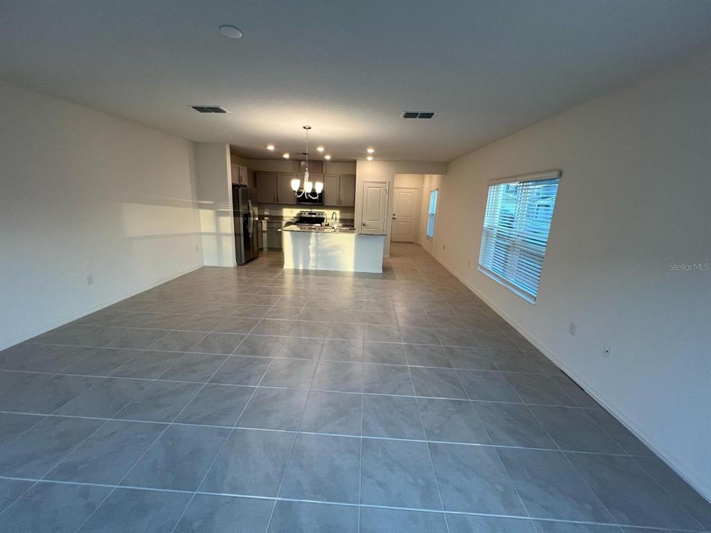 An open-concept living area features light gray tile flooring, a kitchen island, and recessed lighting — 680 STONEY POINT CIRCLE, DAVENPORT, FL