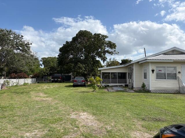 A light-colored house with a screened porch sits on a large, grassy lot — 522 E Ventura Avenue, Clewiston FL 33440, CLEWISTON, FL