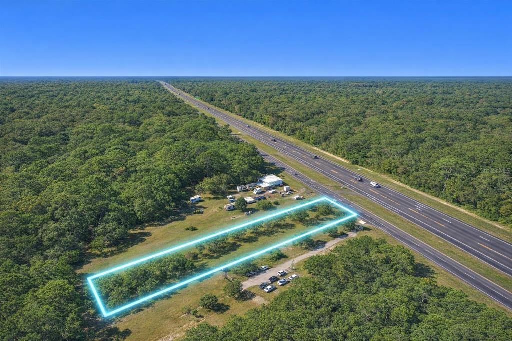 An aerial view shows a rectangular plot of land outlined in blue beside a highway — 8999 S SUNCOAST BOULEVARD, HOMOSASSA, FL