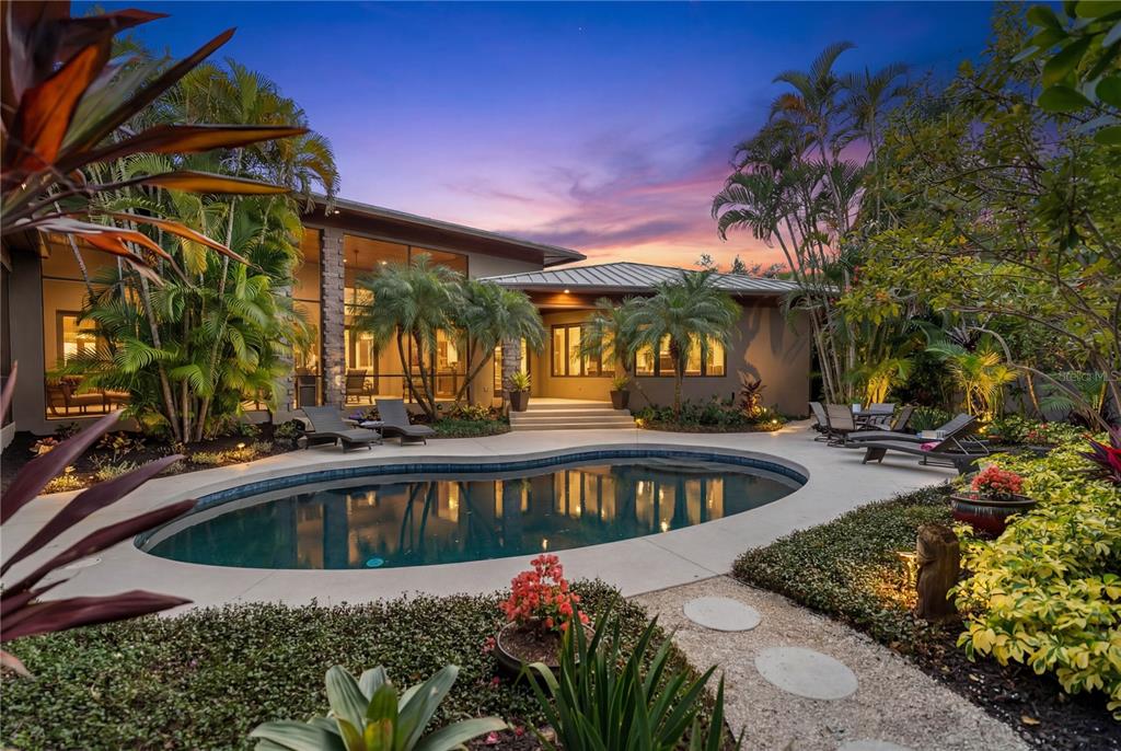 A modern house with a pool, patio, and lush landscaping at sunset — 1804 N LAKE SHORE DRIVE, SARASOTA, FL