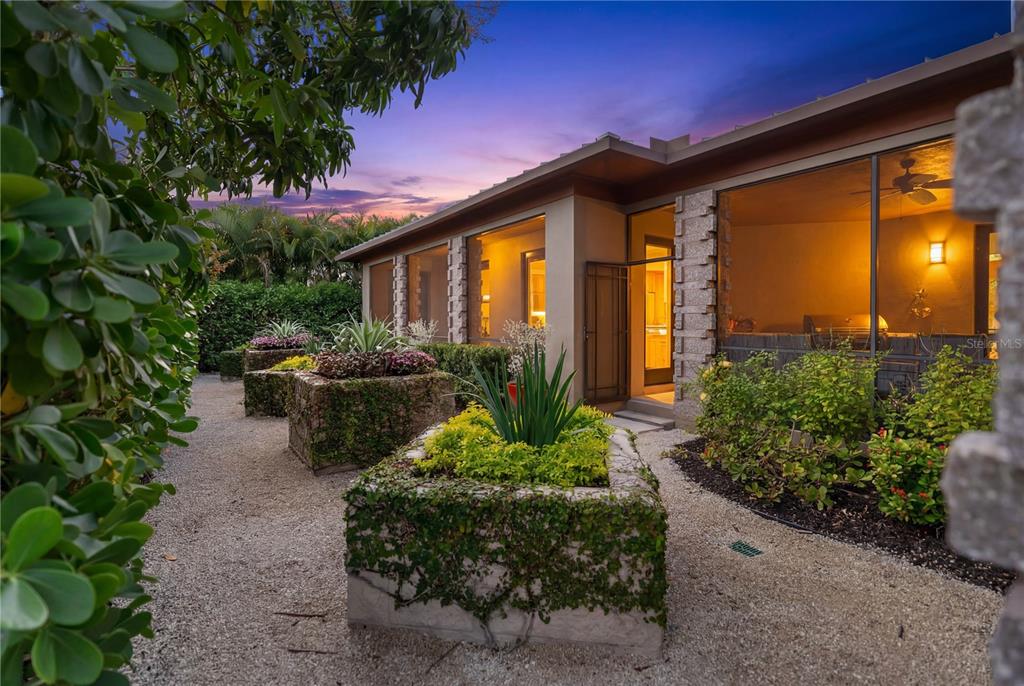 A gravel path leads past stone planters toward a house with a screened-in patio — 1804 N LAKE SHORE DRIVE, SARASOTA, FL
