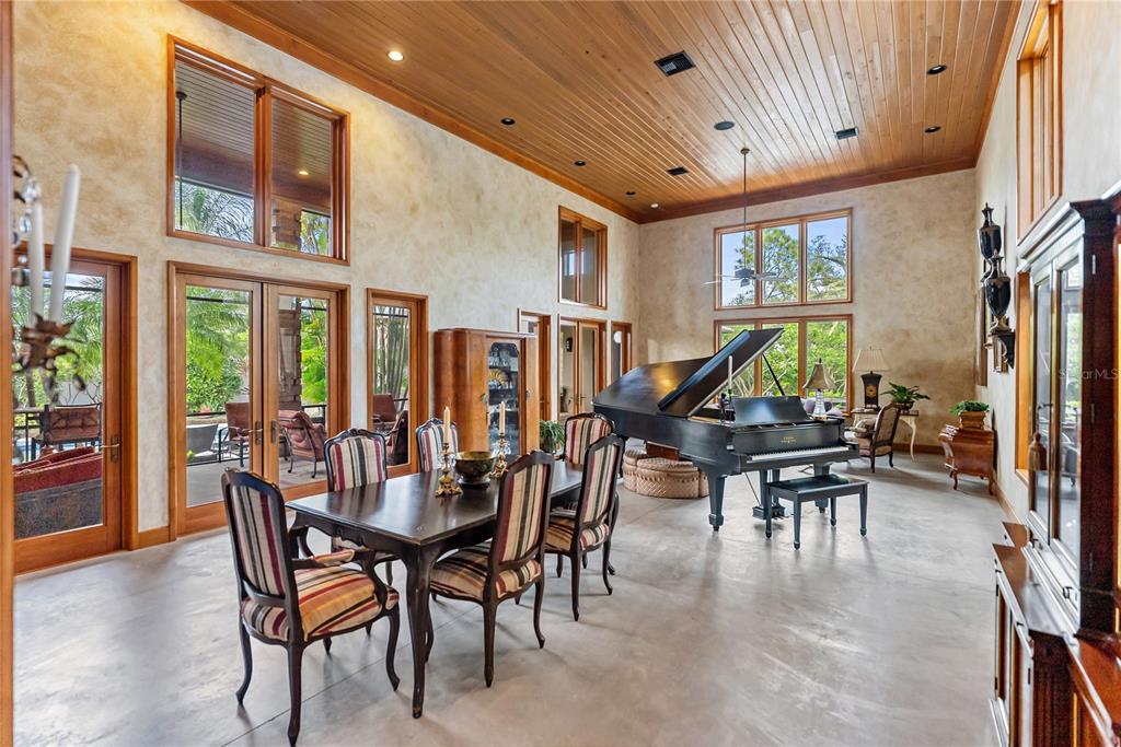 A spacious dining room features a grand piano, wood-paneled ceiling, and large windows — 1804 N LAKE SHORE DRIVE, SARASOTA, FL