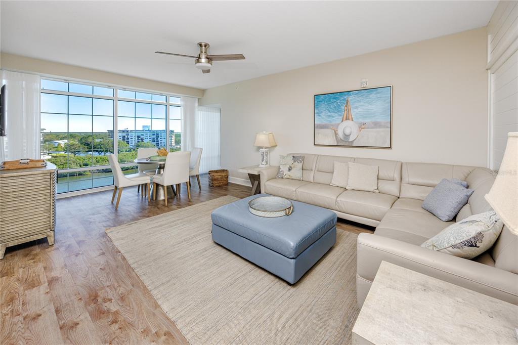 A living room with a beige sectional, blue ottoman, and large windows overlooking a waterway — 399 2ND STREET UNIT 718, INDIAN ROCKS BEACH, FL