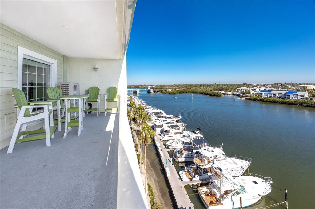 A balcony with green chairs overlooks a marina filled with boats on a sunny day — 399 2ND STREET UNIT 718, INDIAN ROCKS BEACH, FL