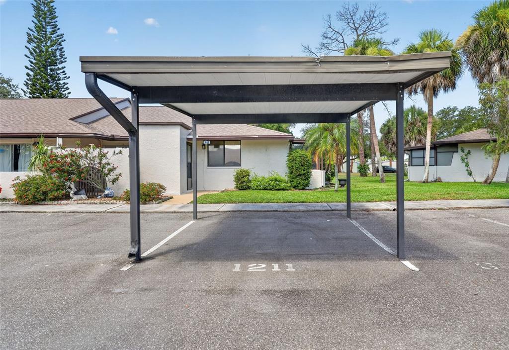 A covered parking carport with the number 1211 painted on the asphalt surface — 1211 11TH CIRCLE SE, LARGO, FL