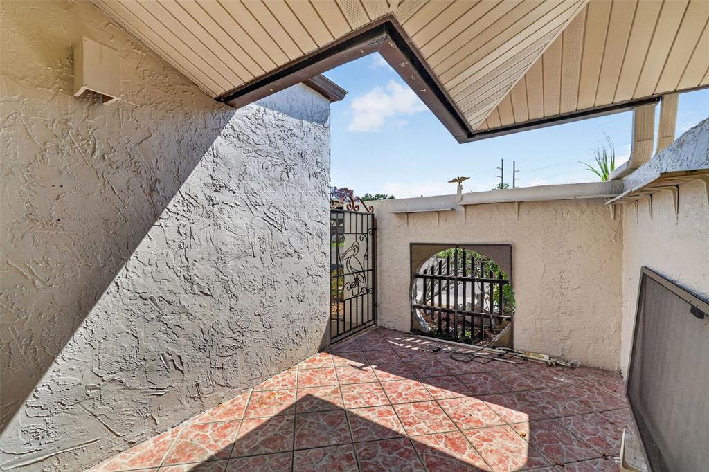 A covered outdoor patio with tiled flooring, a decorative metal gate, and a circular window — 1211 11TH CIRCLE SE, LARGO, FL