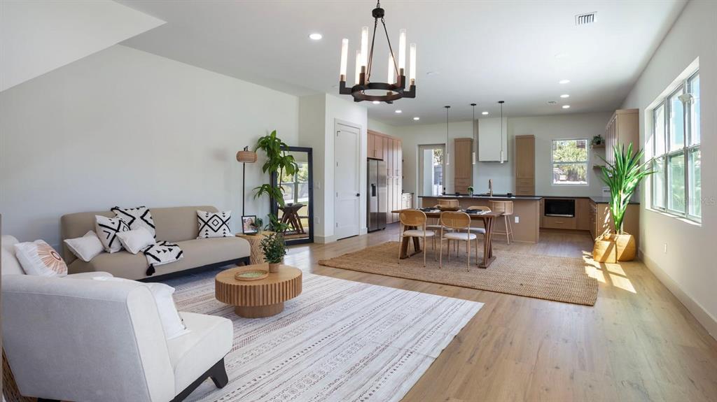 An open-concept living and dining area features light wood floors, neutral furniture, and a chandelier — 1505 W ARCH STREET UNIT 2, TAMPA, FL