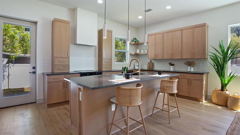 A modern kitchen features light wood cabinets, a dark island countertop, and three pendant lights — 1505 W ARCH STREET UNIT 2, TAMPA, FL
