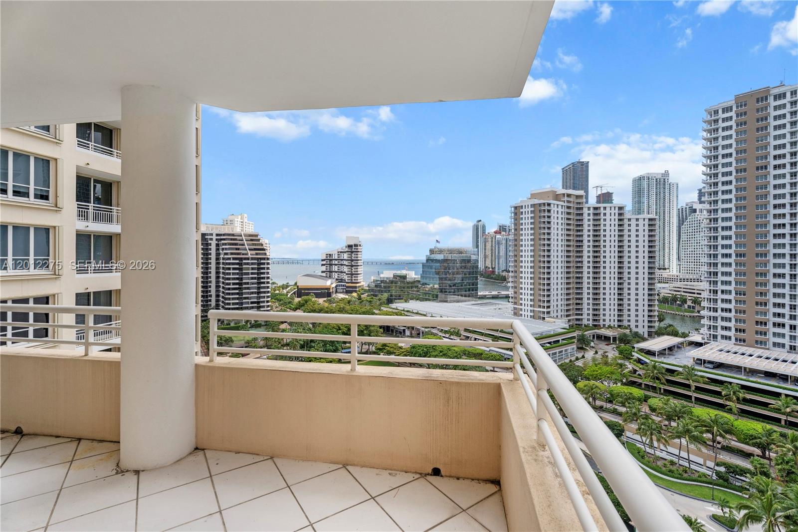 A high-rise balcony with white tile flooring overlooks a city skyline and a bay — 888 Brickell Key Dr # 1702, Miami FL 33131, MIAMI, FL