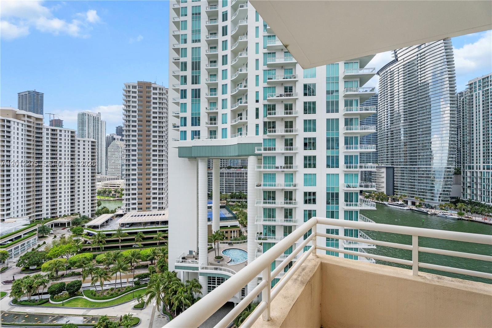 A view from a balcony overlooking a high-rise building, a swimming pool, and a waterway — 888 Brickell Key Dr # 1702, Miami FL 33131, MIAMI, FL