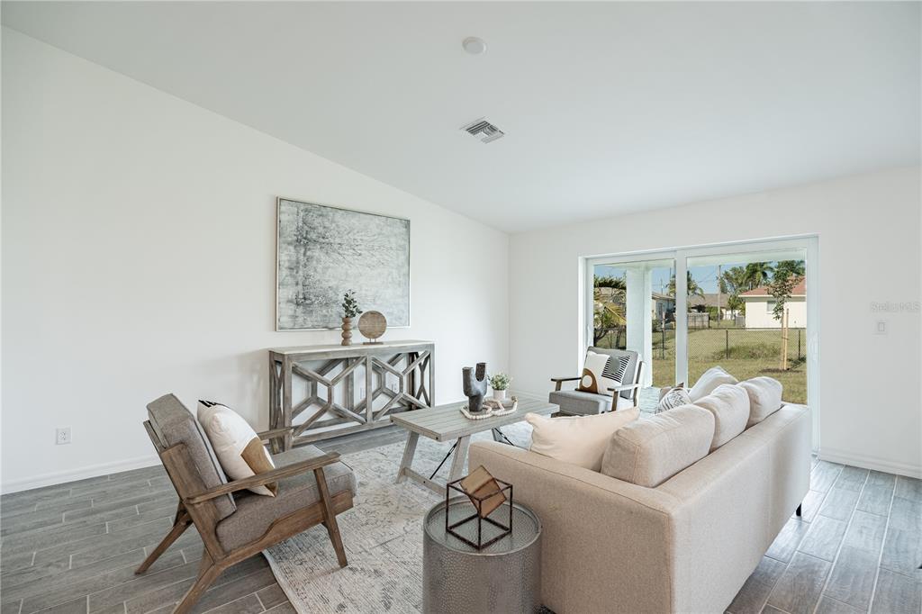 A living room features a sofa, armchairs, a wooden console table, and sliding glass doors — 2043 BROAD RANCH DRIVE, PORT CHARLOTTE, FL