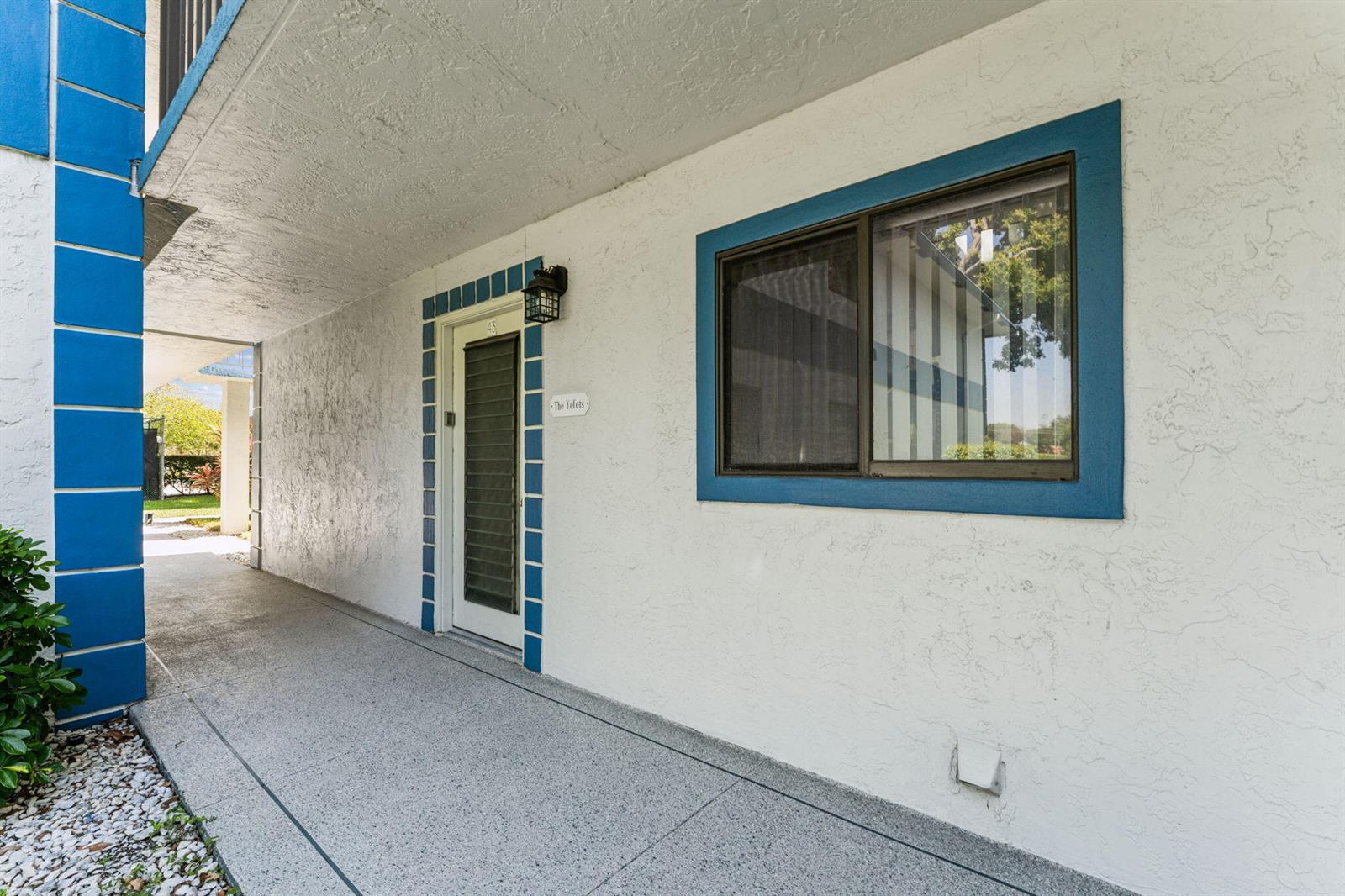 An exterior view of a building entrance with a white wall, blue trim, and a window — 15301 Pembridge Avenue # 43, Delray Beach FL 33484, DELRAY BEACH, FL