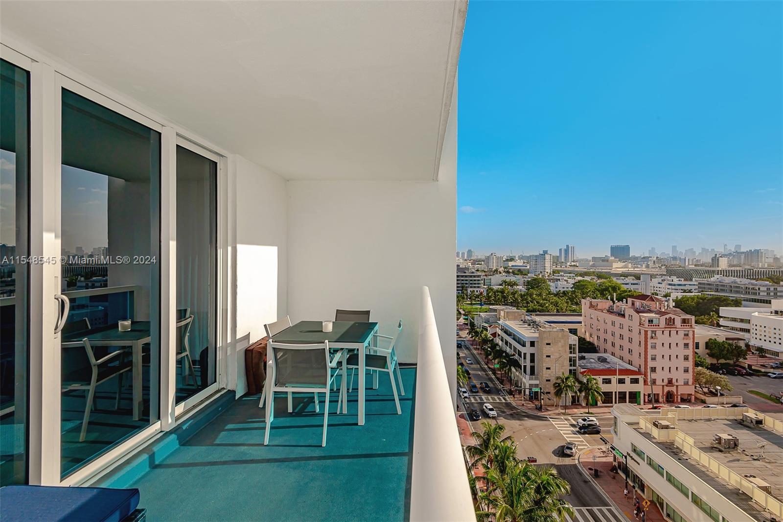 A balcony with a dining set overlooks a city street and urban skyline — 2301 Collins Ave # 1230, Miami Beach FL 33139, MIAMI BEACH, FL