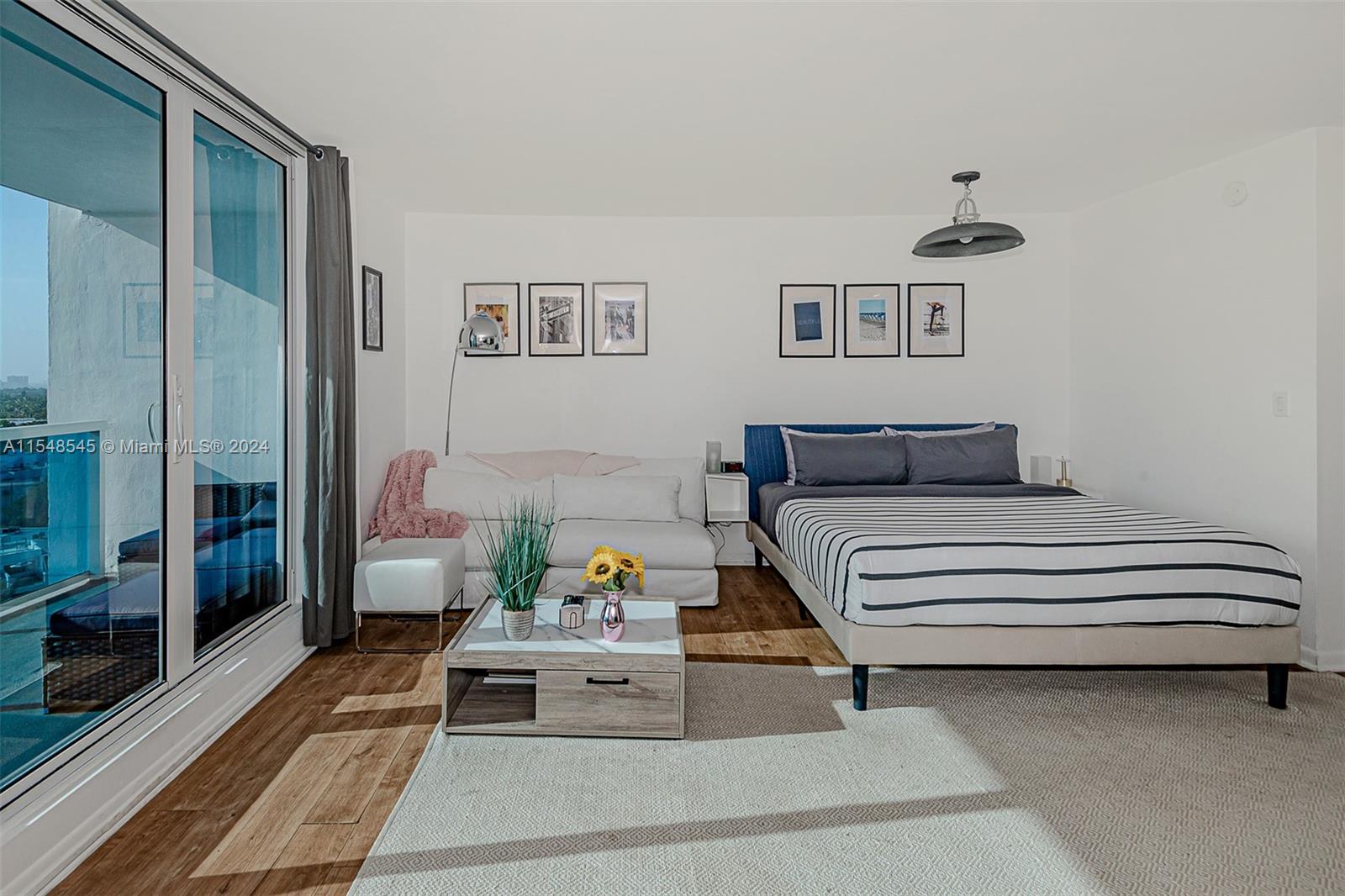 A bedroom features a bed, a small sofa, a coffee table, and a glass balcony door — 2301 Collins Ave # 1230, Miami Beach FL 33139, MIAMI BEACH, FL