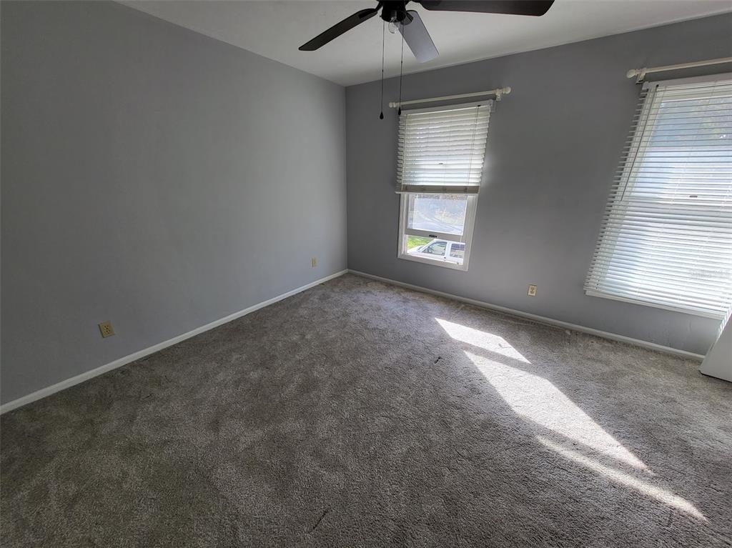 An empty bedroom with gray walls, gray carpet, a ceiling fan, and two windows — 3727 SW 28TH TERRACE UNIT 2, GAINESVILLE, FL