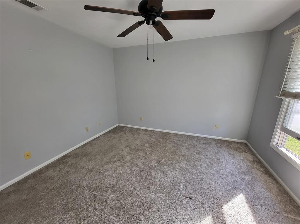 An empty bedroom features gray walls, beige carpeting, and a ceiling fan — 3727 SW 28TH TERRACE UNIT 2, GAINESVILLE, FL