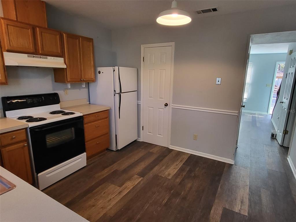 A kitchen features wood cabinets, a white stove, a refrigerator, and wood-look flooring — 3727 SW 28TH TERRACE UNIT 2, GAINESVILLE, FL
