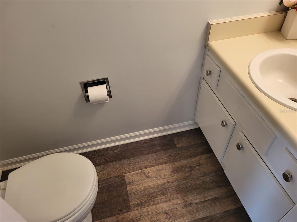 A bathroom features a white toilet, a vanity with a beige countertop, and wood-look flooring — 3727 SW 28TH TERRACE UNIT 2, GAINESVILLE, FL