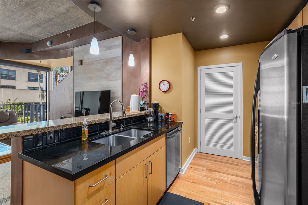 A kitchen with light wood cabinets, black countertops, stainless steel appliances, and a white door — 155 S COURT AVENUE UNIT 1104, ORLANDO, FL