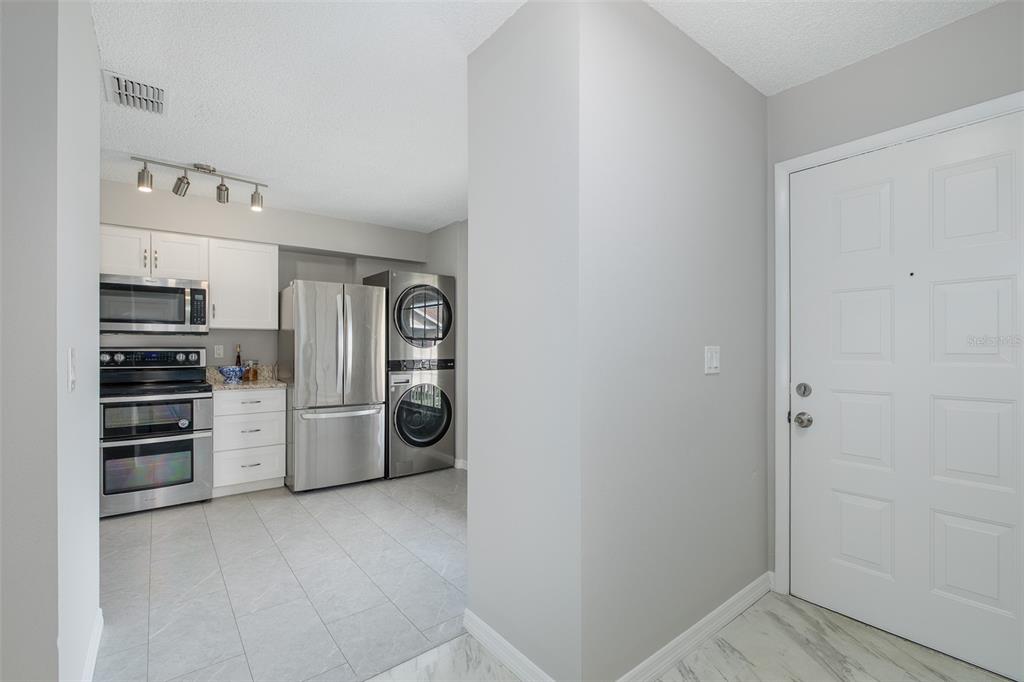 A kitchen with stainless steel appliances and white cabinets sits adjacent to a white door — 4933 MYRTLE OAK DRIVE UNIT 23, NEW PORT RICHEY, FL