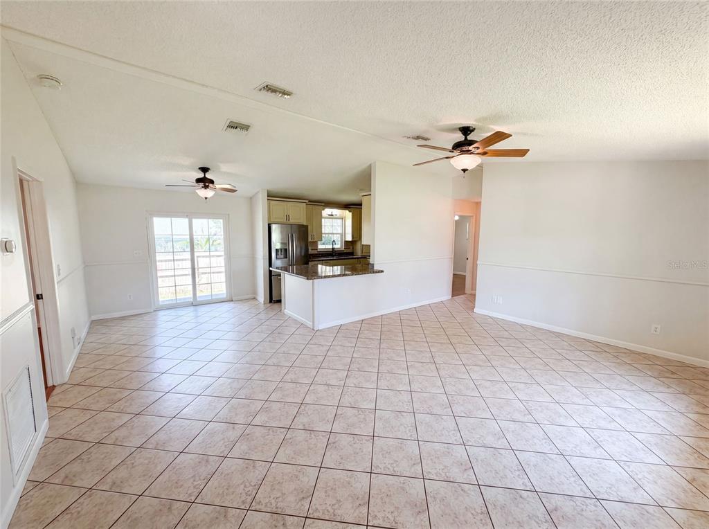 An open-concept living and dining area features tile flooring, a kitchen island, and ceiling fans — 7820 HIGHWAY A1A, MELBOURNE BEACH, FL