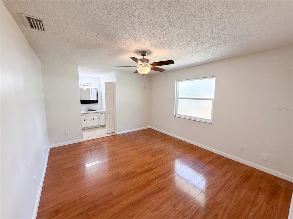 An empty bedroom features wood-look flooring, a ceiling fan, and an attached bathroom — 7820 HIGHWAY A1A, MELBOURNE BEACH, FL
