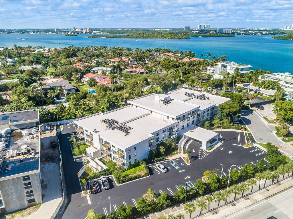 An aerial view of a multi-story apartment building with a parking lot and waterfront surroundings — 10250 Collins Avenue # 408, Bal Harbour FL 33154, BAL HARBOUR, FL